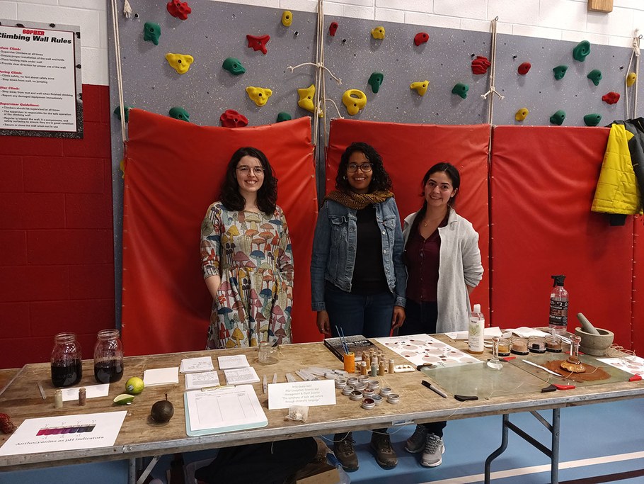 (Left to right) Marissa Kopp, Zoelie Rivera-Ocasio and Leidy Fernandez share soil and plant-based paints with local elementary school students at a Science and Technology Fair. Students learned about the diversity of soils and the process of making the paints, including separating clay particles, and using binders such as acacia gum.